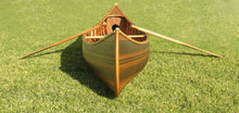 Load image into Gallery viewer, A wooden canoe with a curved bow and matte finish, displayed on grass.