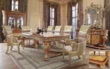 Load image into Gallery viewer, A 7-piece dining table set with a bright gold and medium golden tan finish, featuring intricate woodwork and upholstered chairs in a grand room.
